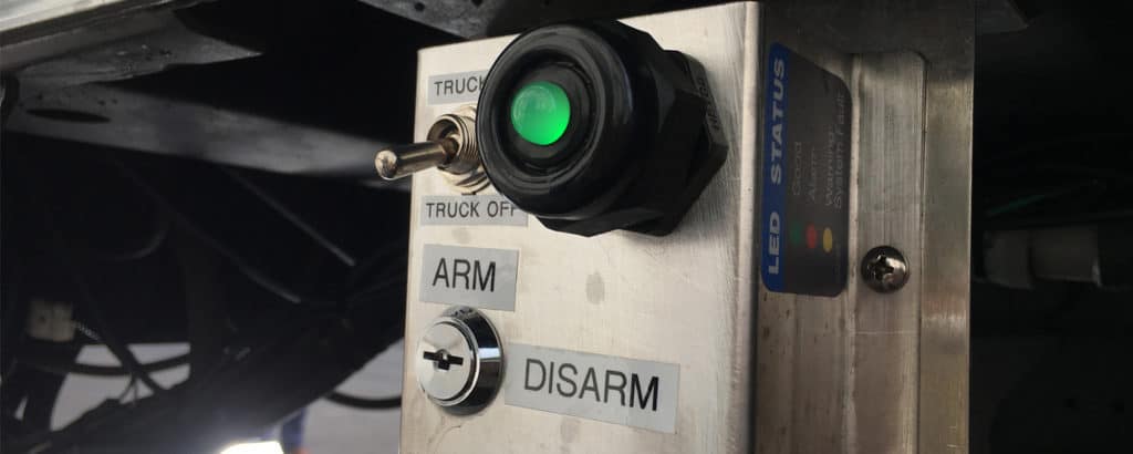 SafeFreight silver cargo theft control box with green light, on-off switch and a arm/disarm keyhole